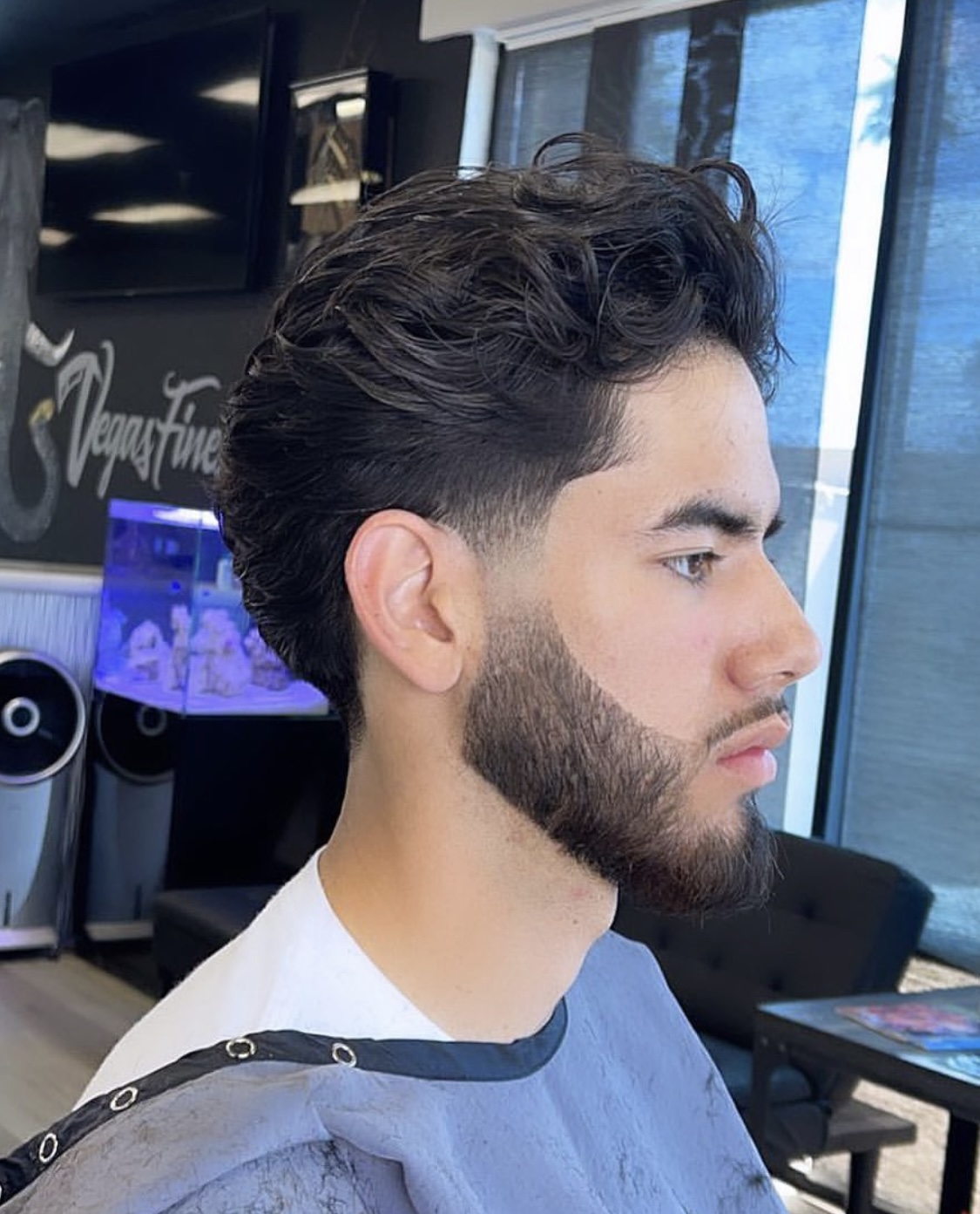 Side profile of a men's wavy haircut with faded sides and beard trim